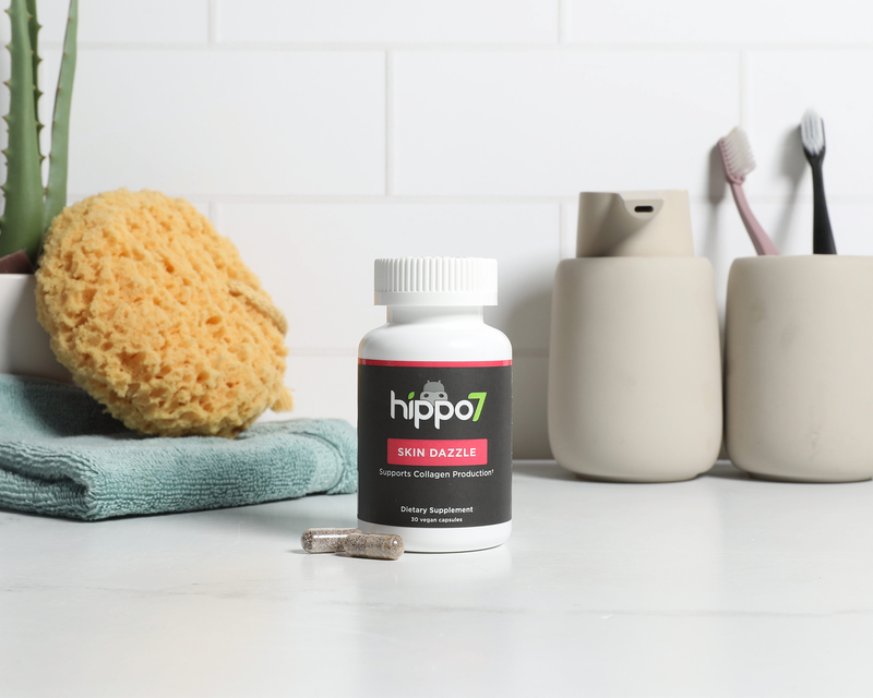Skin Dazzle vegan collagen support supplement in the bathroom next to sponge and tooth brush