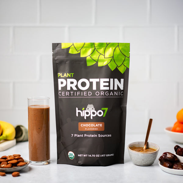 Chocolate flavored Plant protein in pouch and and also mixed in glass with almonds, dates, bananas and oranges, cover image